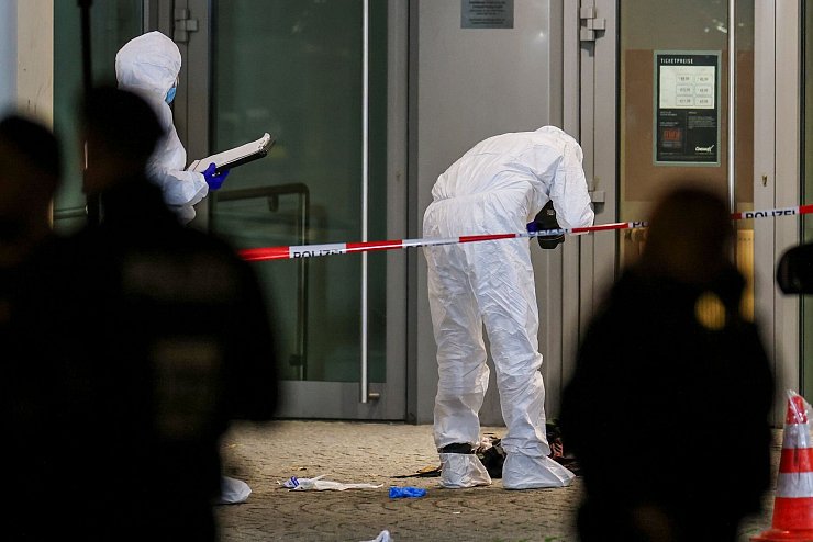 Beamte in weißen Schutzanzügen fotografieren blutige Kleidungsstücke und zertrümmerte Glasscheiben. - © Christoph Reichwein/dpa