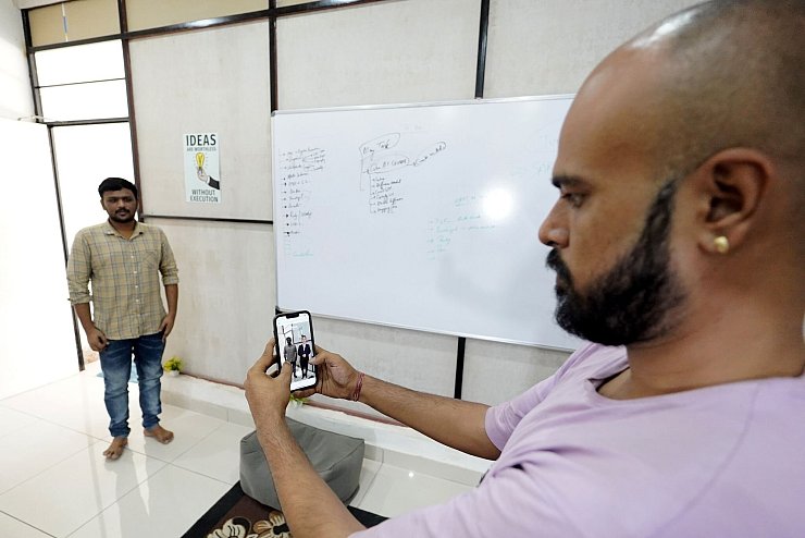 Der Eigentümer der Firma Polymath Synthetic Media Solutions, Divyendra Singh Jadoun, demonstriert mit einem Kollegen wie Leute Selfies mit Politiker-Avataren in ihrer gewohnten Umgebung machen können. - © Himanshu Sharma/dpa