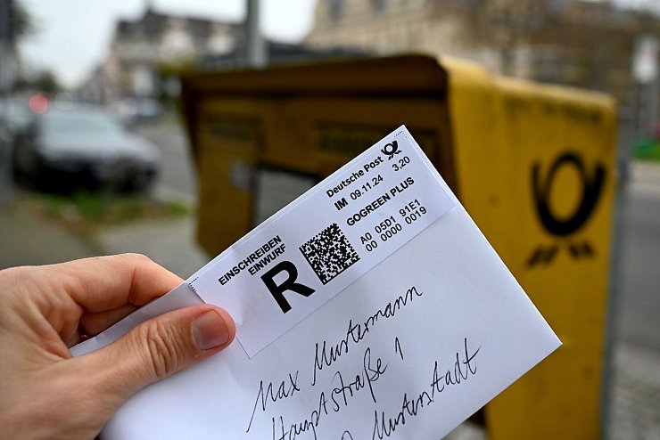 Ein Mann hält ein sogenanntes Einwurf-Einschreiben vor einen Briefkasten (gestellte Szene). - © Wolf von Dewitz/dpa