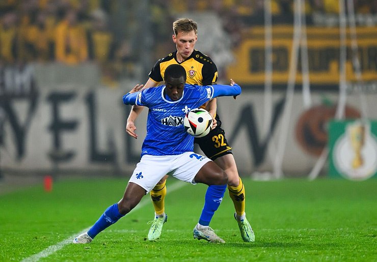 Dynamos Jonas Sterner spielt gegen Darmstadts Merveille Papela den Ball mit der Hand. - © Robert Michael/dpa
