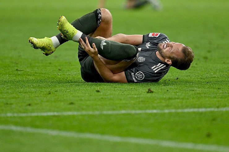 Bayern-Stürmer Harry Kane hält sich nach einem Zweikampf den Knöchel. - © Sven Hoppe/dpa