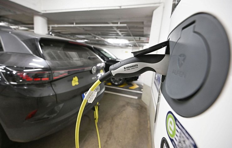 Ein Elektrofahrzeug ist in einer Tiefgarage mit einem Stromkabel zum Laden an eine E-Ladesäule angeschlossen. - © Bernd Weißbrod/dpa
