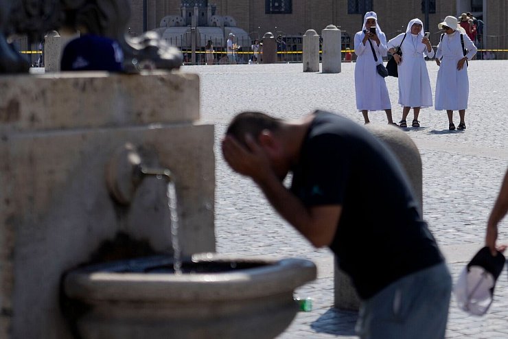 Ein Mann erfrischt sich an einem Brunnen auf dem Petersplatz, während die Temperaturen bis zu 38 Grad Celsius im Vatikan erreichen. - © Gregorio Borgia/AP/dpa
