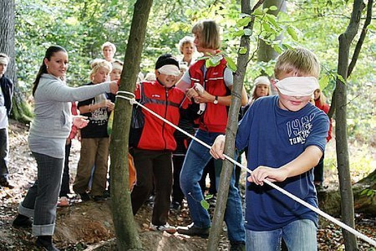 Mit verbundenen Augen: Am "blinden Pfad" tasten sich die Schüler an einem Seil um Bäume herum. Diese Station betreuen Marina Suprun (links) und Michaela Radeck.Foto: Gröne
