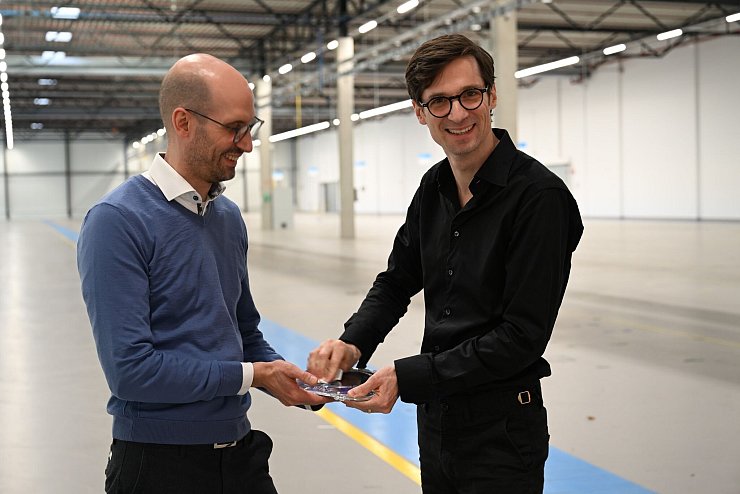 Noch ist die Halle hinter ihnen leer, bald sollen dort aber Reinräume zur Wafer-Produktion installiert werden. - © Wolf von Dewitz/dpa