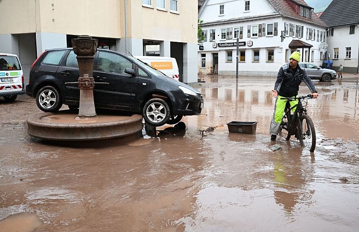 Auf einem Brunnen in Rudersberg steht ein durch ein Hochwasser weggespültes Auto. - © Bernd Weißbrod/dpa