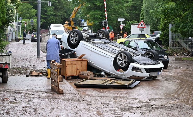 Auf einer Straße in Rudersberg liegt ein durch ein Hochwasser umgestürtztes Auto auf dem Dach. - © Bernd Weißbrod/dpa