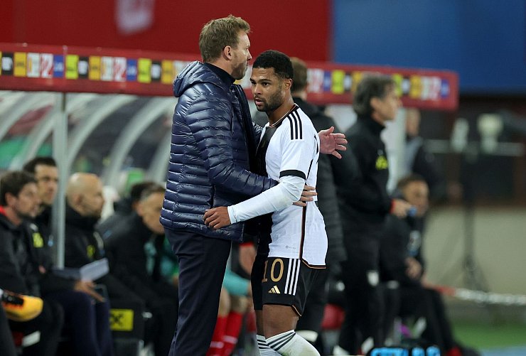 Wieder vereint: Bundestrainer Julian Nagelsmann (l) und Serge Gnabry, hier bei dessen bislang letzten Länderspieleinsatz in Österreich im November 2023. - © Christian Charisius/dpa