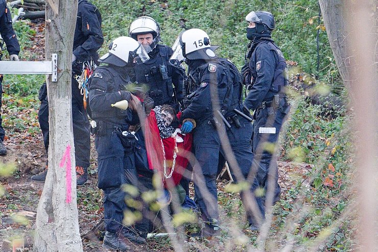 Polizisten tragen einen Aktivisten aus dem sogenannten Sündenwäldchen. - © Henning Kaiser/dpa