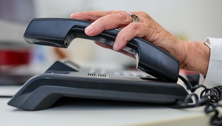 Eine Frau nimmt einen Telefonhörer in die Hand. - © Jan Woitas/dpa