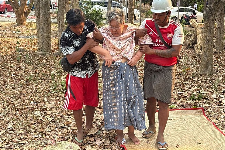 Rettungskräfte helfen einer verletzten Frau, die nach einem Erdbeben unter einem Gebäude eingeschlossen war. - © Aung Shine Oo/AP/dpa