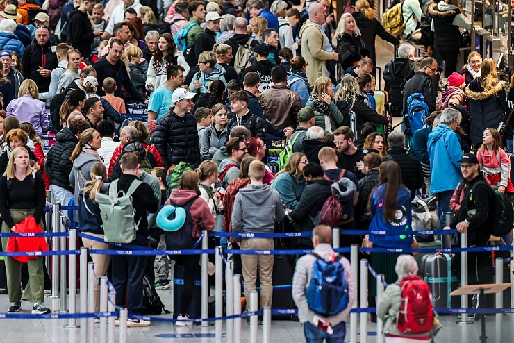 Am Flughafen in Düsseldorf stehen Reisende am Samstagmorgen mit ihren Koffern im Abflug-Terminal vor den Check-In-Schaltern. - © Christoph Reichwein/dpa