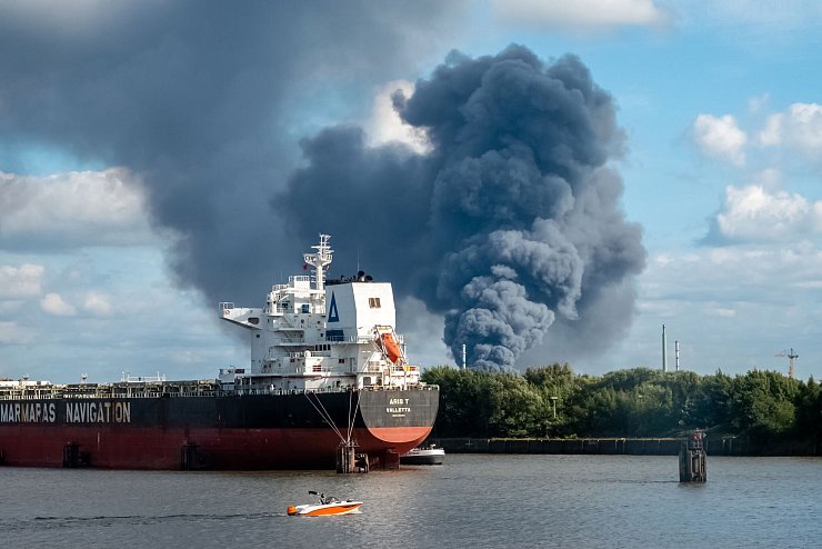 Rauch ist hinter einem Schiff zu sehen; in der Nähe des Einsatzortes fließt die Norderelbe. - © Bodo Marks/dpa