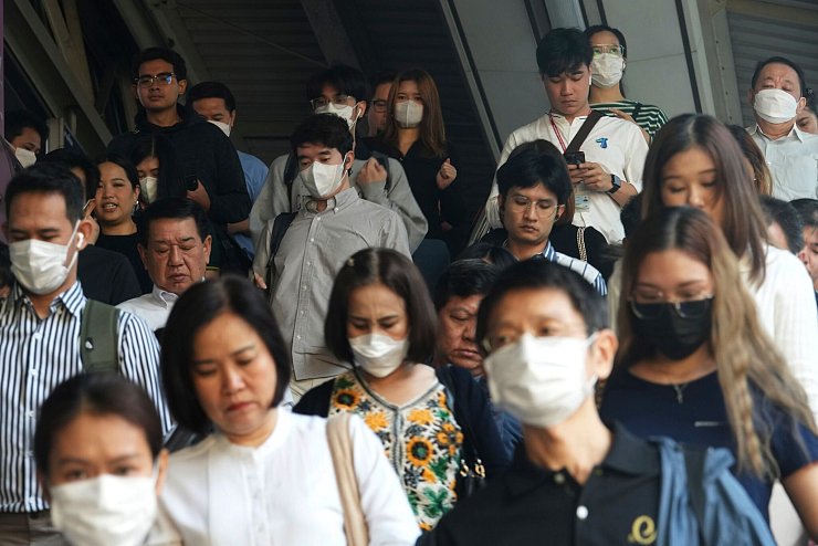 Pendler tragen Gesichtsmasken, um sich vor der Luftverschmutzung zu schützen. - © Sakchai Lalit/AP/dpa