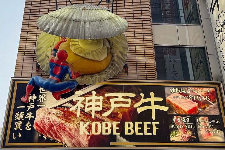 Nur eine von vielen Fassaden-Dekorationen in Dotonbori: ein «Spiderman», der es mit einer Jakobsmuschel zu tun bekommt. - © Ralf Johnen/dpa-tmn
