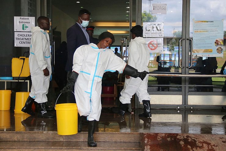 Eine Mitarbeiterin trägt Desinfektionsmittel aus einem Cholera-Behandlungszentrum (Archivbild) - © --/AP/dpa