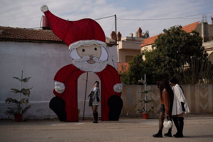 Eine junge Frau posiert für ein Foto an einer Weihnachtsdekoration auf einem Platz in einem christlichen Viertel in der syrischen Stadt Homs. - © Leo Correa/AP/dpa