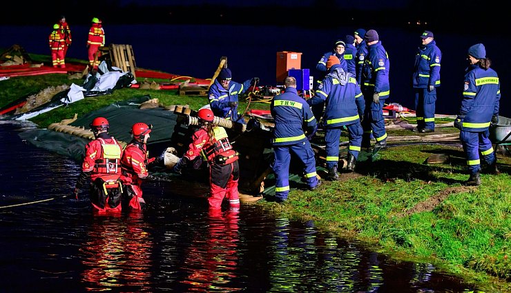 Ehrenamtliche Einsatzkräfte vom THW und der DLRG befestigen einen Deich in Niedersachsen. - © Philipp Schulze/dpa