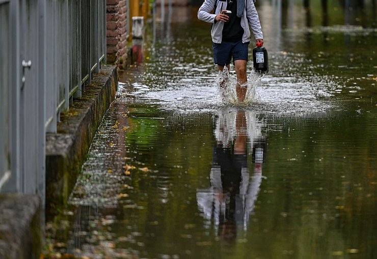 Ein Anwohner einer überfluteten Straße in Frankfurt Oder watet durch das Wasser. - © Patrick Pleul/dpa