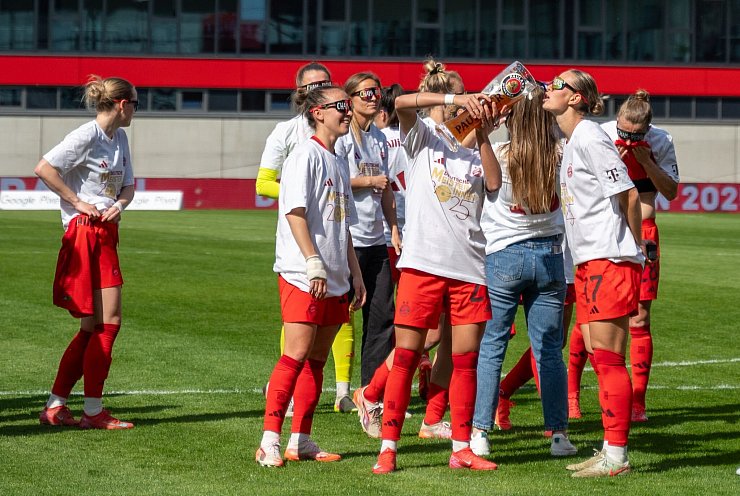 In Meister-Shirts und mit Bier feiern die Bayern-Fußballerinnen den Titel. - © Leonie Asendorpf/dpa
