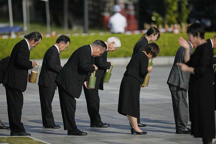 Teilnehmer der Gedenkveranstaltung in Hiroshima halten eine Schweigeminute ab. - © Louise Delmotte/AP/dpa