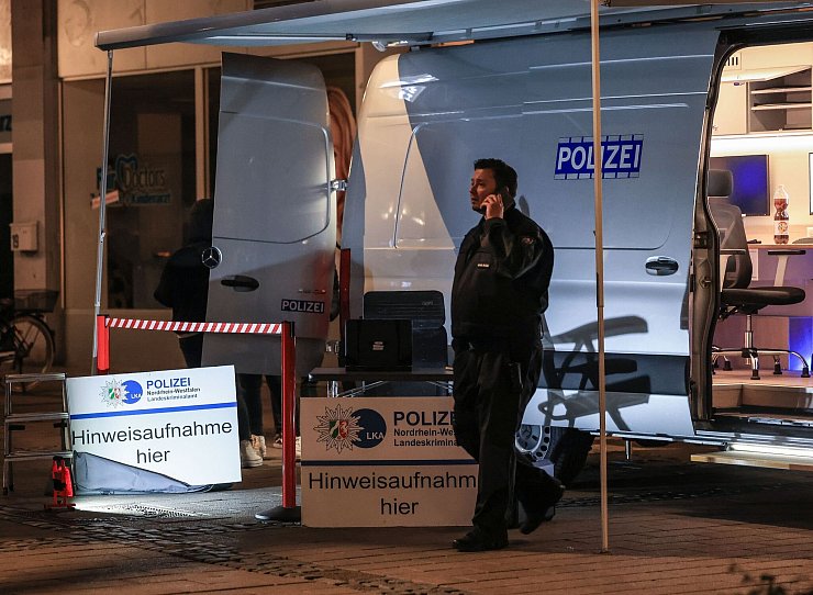Ein Polizist steht in der Nähe des Tatortes vor einem Einsatzfahrzeug. - © Oliver Berg/dpa