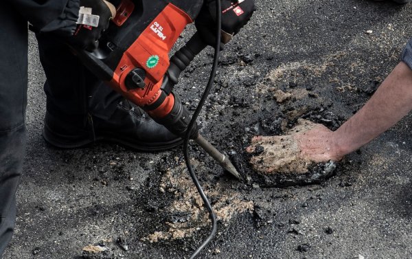 Bei einer Blockade der Gruppe Letzte Generation auf der Stadtautobahn unweit des Kurfürstendamms in Berlin wird ein Aktivist, der sich mit einem besonderen Gemisch auf die Straße festgeklebt hatte, mit schwerem Gerät von der Polizei von der Straße gelöst. - © Paul Zinken/dpa