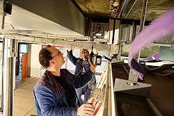 Passt, wackelt und hat Luft: Die beiden L&uuml;ftungsbauer Frank Ortmann (vorne) und Jakob Mantler bringen unter der Decke im Hauptschultrakt eine weitere Brandschutzklappe an. Foto: Backe