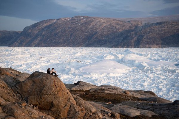 Zwei Studenten der New York University sitzen auf einem Felsen mit Blick auf den grönländischen Helheim-Gletscher. - © Felipe Dana/AP/dpa