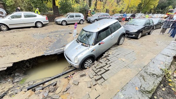 Böse Überraschung für diesen Autofahrer: Nach einem Wasserrohrbruch ist sein Auto in ein unterspültes Loch gerutscht. - © Feuerwehr Dortmund/dpa