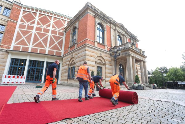 Der rote Teppich wird vor dem Bayreuther Festspielhaus ausgerollt. - © Karl-Josef Hildenbrand/dpa