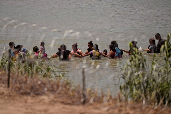 Migranten überqueren Hand in Hand den Fluss Rio Grande zwischen Mexiko und den USA. - © Eric Gay/AP