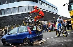 W&auml;hrend Tim Junklewitz auf den Kleinwagen springt, steht sein &auml;lterer Bruder Jan rechts daneben auf seinem Motorrad. Die Trial-Biker zeigten ihr K&ouml;nnen auf dem Parkplatz hinter dem neuen ADAC-Geb&auml;ude (im Hintergrund). - &copy; FOTOS: BARBARA FRANKE