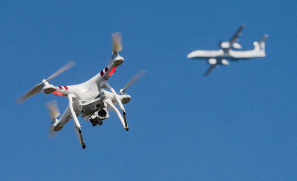 Eine Drohne fliegt in weiter Entfernung von einem Flugzeug, das im Anflug auf den Flughafen Düsseldorf ist. (Symbolbild) - © Julian Stratenschulte/dpa