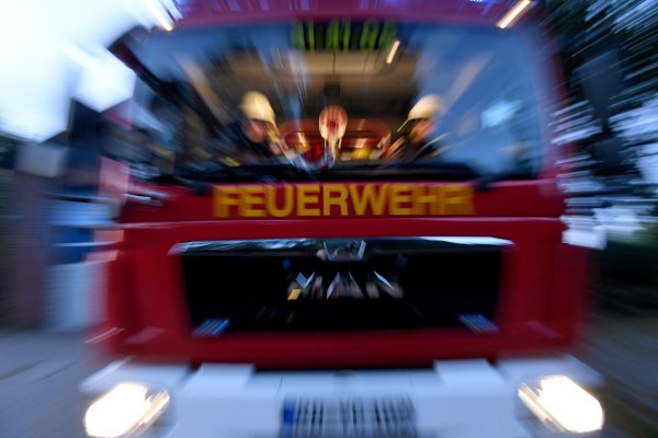 Einsatzkräfte der Feuerwehr sitzen in ihrem Fahrzeug. - © Carsten Rehder/dpa
