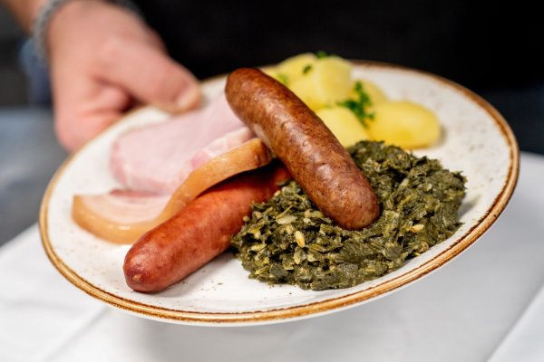 Saftig und deftig: Eine Portion Grünkohl mit den traditionellen Beilagen Salzkartoffeln, Kochwurst, Pinkelwurst und Kasseler - serviert in einem Oldenburger Restaurant. - © Hauke-Christian Dittrich/dpa/dpa-tmn