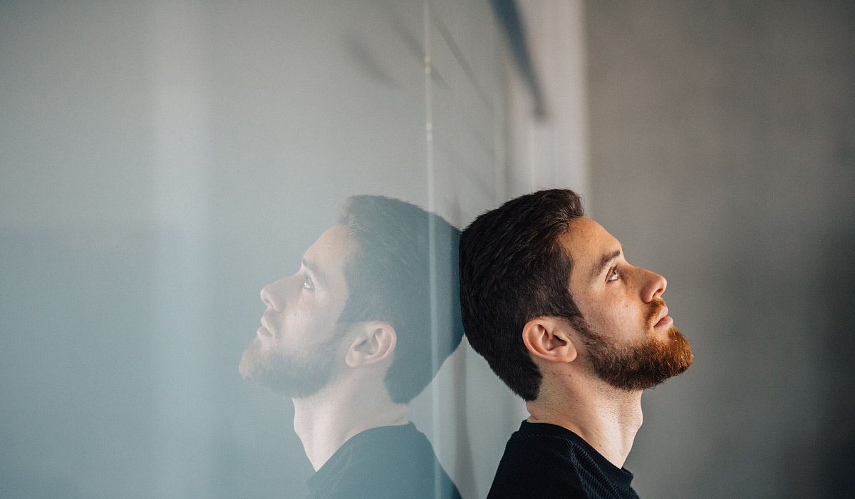 Ein junger Mann lehnt nachdenklich an einer Glaswand - Zacharie Scheurer/dpa-tmn