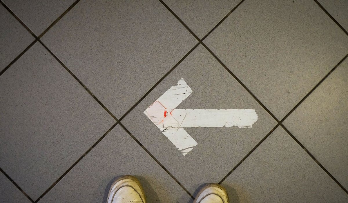 Ein Pfeil aus Klebeband ist auf einem Fußboden zu sehen - Sebastian Willnow/dpa/dpa-tmn