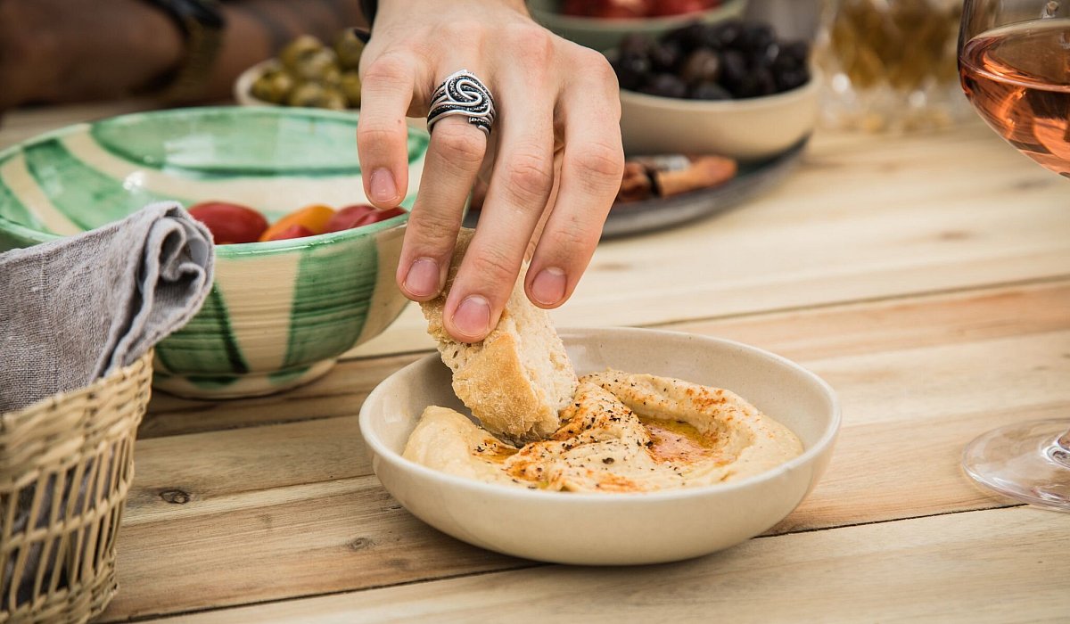 Ein Mann dippt ein Stück Brot in Hummus - Christin Klose/dpa-tmn
