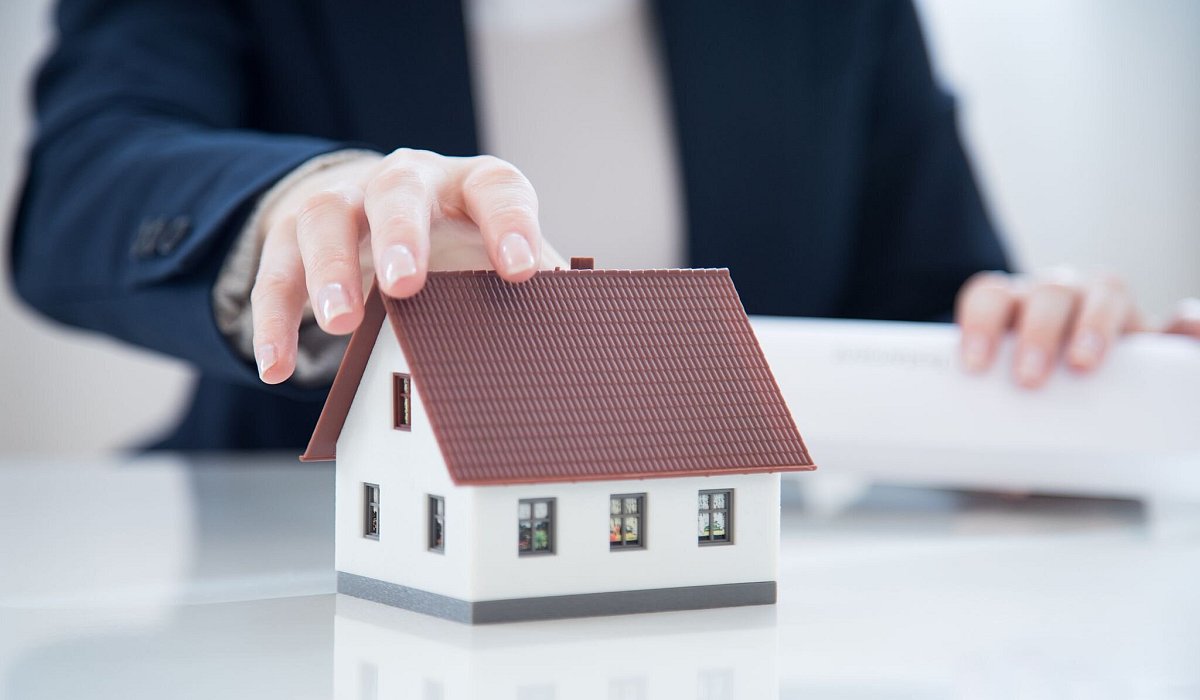 Ein Mann greift nach einem Modellhaus - Christin Klose/dpa-tmn