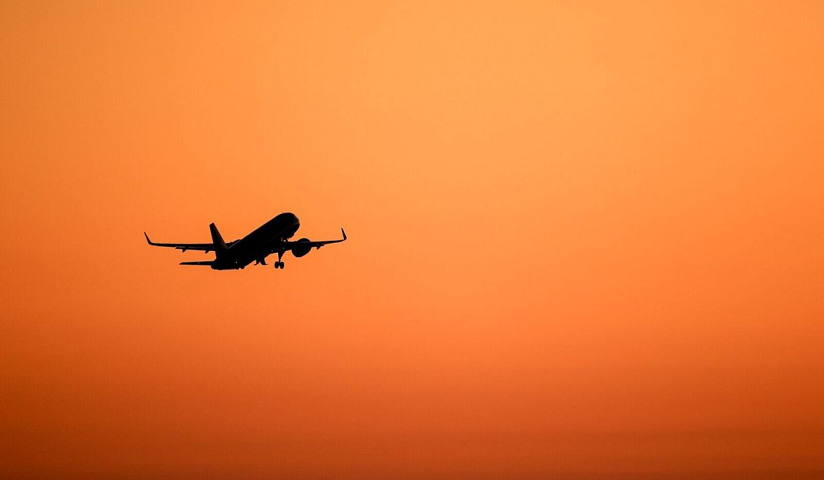 Ein Flugzeug hebt vor orangefarbenem Himmel ab - Jan Woitas/dpa/dpa-tmn