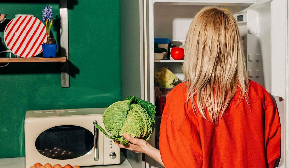 Eine Frau h&auml;lt einen Kohl vor einem offenen K&uuml;hlschrank - Vira Simon/Westend61/dpa-tmn