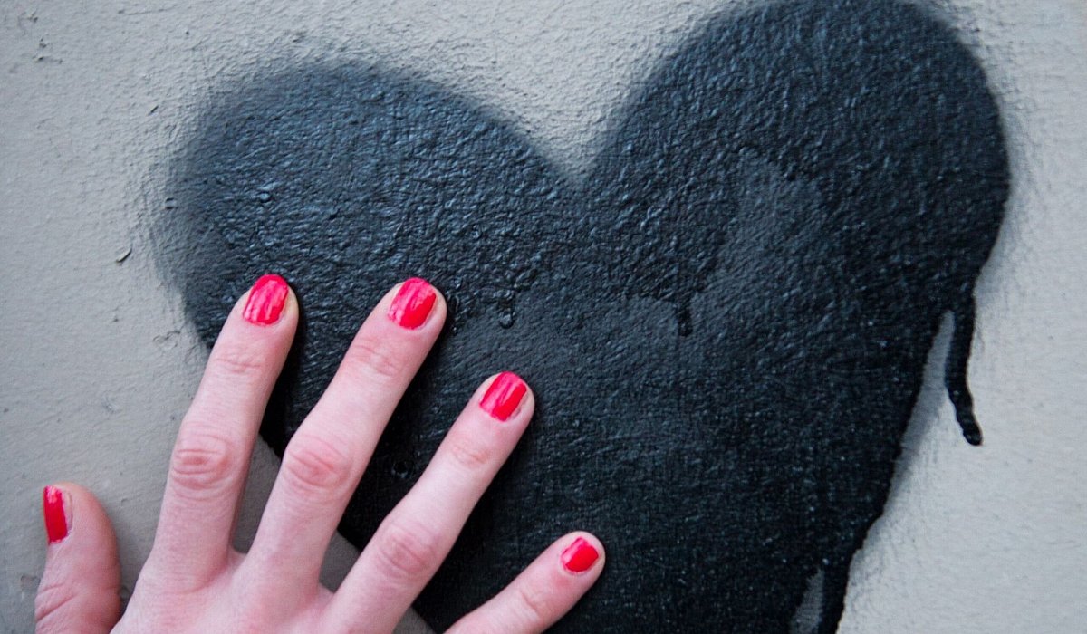Frauenhand berührt ein auf die Wand gesprühtes Herz - Inga Kjer/dpa/dpa-tmn