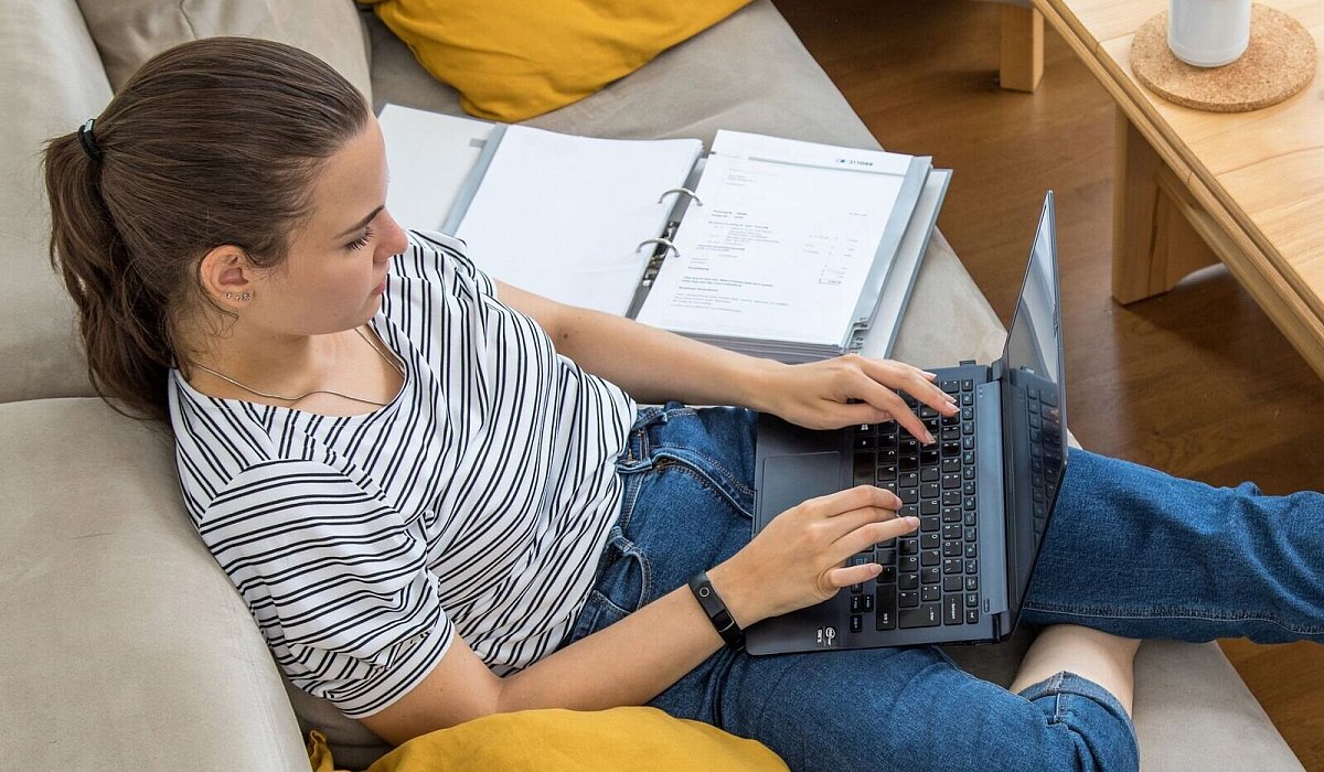 Eine Frau sitzt mit Laptop und Aktenordnern auf einem Sofa - Christin Klose/dpa-tmn