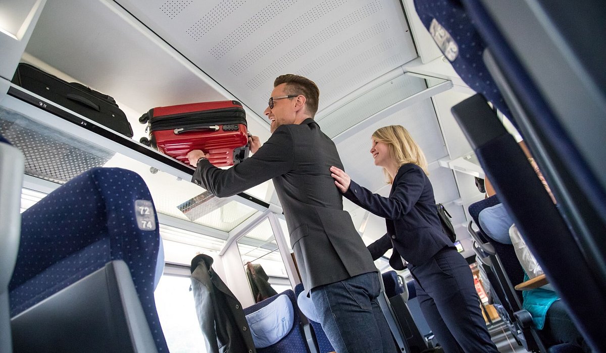 Ein Mann verstaut sein Gep&auml;ck &uuml;ber seinem Sitzplatz im Zug - Christin Klose/dpa-tmn