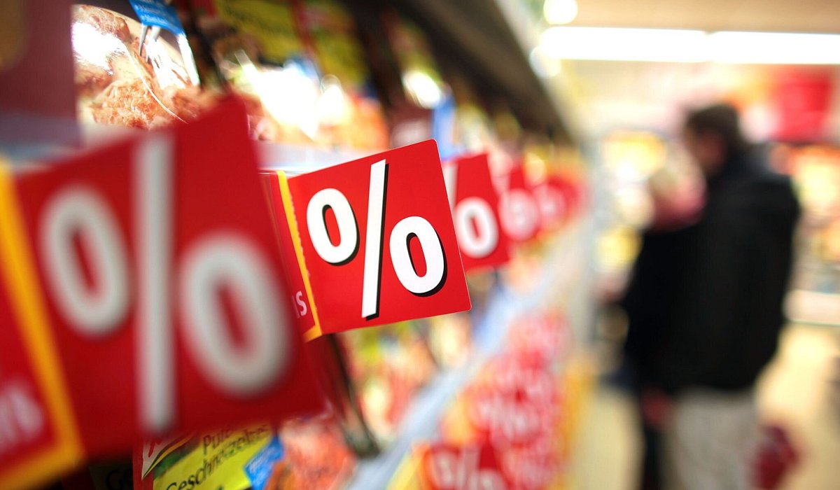Prozentzeichen hängen in einem Supermarkt an Regalen - Oliver Berg/dpa/dpa-tmn