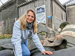 Vorsitzende Melanie Schneider sitzt auf einem Haufen von Kunstrasenrollen für den Auslaufplatz ihrer kranken Pferde. - © Burkhard Battran