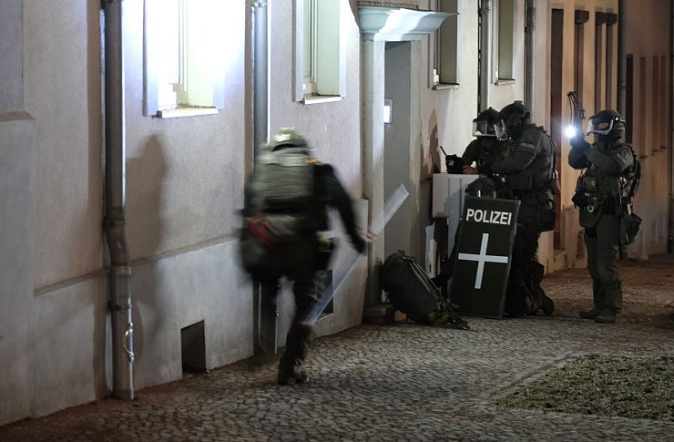 Spezialkräfte der Polizei stehen vor einem Mehrfamilienhaus in Bernburg in Sachsen-Anhalt, das in Zusammenhang mit der tödlichen Attacke auf den Weihnachtsmarkt in Magdeburg stehen soll. - © Sebastian Willnow/dpa