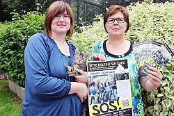 Hilferuf: Annette Kortekamp (rechts) und Kerstin Sanker mit Plakat und einer jungen Katze, der nach einem Unfall ein Auge entfernt werden musste – einer der Gründe, warum es dem Verein so schlecht geht. - © Foto: Privat