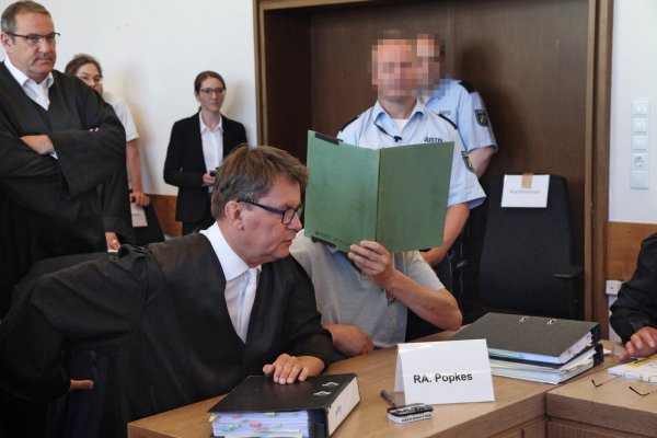 Der Angeklagte Heiko V. verbirgt sein Gesicht hinter einem Aktendeckel. Neben ihm sitzt sein Verteidiger Jann Popkes. Links dahinter ist der Nebenklagevertreter eines Opfers Roman von Alvensleben zu sehen. - © Bernhard Preuß